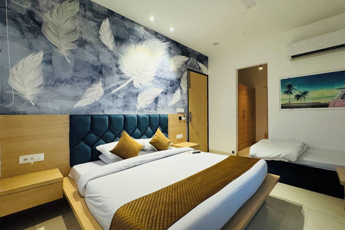 Een moderne hotelkamer met een groot bed, een hoofdeinde met een bladmotief, een nachtkastje en een schilderij aan de muur.