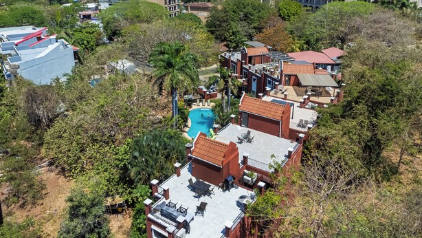 A resort with multiple buildings, a swimming pool, and a view of the ocean. - Tamarindo Escape: Exquisite One-Bedroom Condo (Tamarindo)