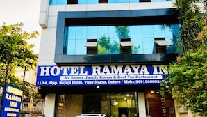 En moderne hotelbygning med skilt for Hotel Ramaya Inn, der tilbyder værelser, familieværelser og en tagrestaurant.
