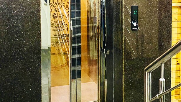En elevator med glasdør, digitalt display og metalgelænder.
