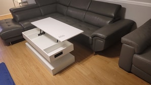 A sectional sofa, a white coffee table, and a white storage unit in a living room.