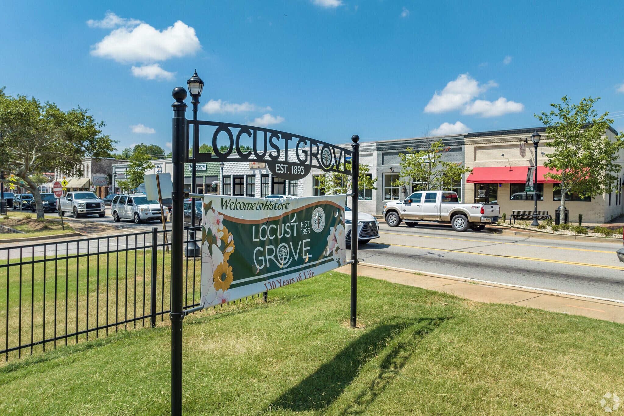 A street sign for Locust Grove with a welcome message and establishment year.