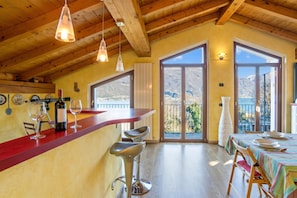 Eine Küche mit Holzbalkendecke, eine Bar mit Hockern und große Fenster mit Blick auf die Berge.