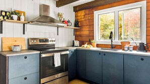 A modern kitchen with a built-in oven, a stainless steel range, and a window with a view of autumn foliage. - NEW:Luxury 4BR Log Cabin surrounded by trees in Hunter. Near Hiking & Waterfalls (Hunter)