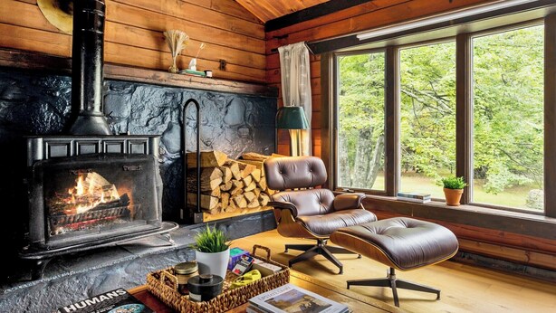 A cozy cabin interior with a fireplace, leather seating, and a large window offering a view of the forest. - NEW:Luxury 4BR Log Cabin surrounded by trees in Hunter. Near Hiking & Waterfalls (Hunter)
