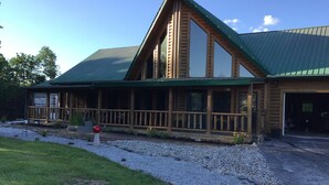 A log cabin with a green metal roof, a covered porch, and a gravel driveway. - Spacious 5 bedrooms, three stories log cabin with WiFi, AC in charming Bronston (Bronston)