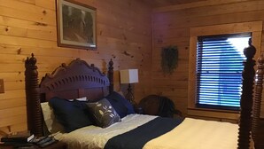 A wooden cabin bedroom with a four-poster bed, a nightstand with a lamp, and a window with blinds. - Spacious 5 bedrooms, three stories log cabin with WiFi, AC in charming Bronston (Bronston)