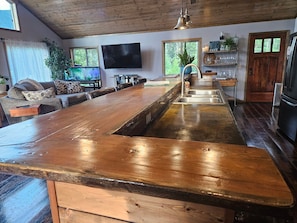 Une cuisine avec un îlot central en bois, un évier encastré et un téléviseur fixé au mur.