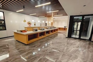 Eine moderne Hotelhalle mit Marmorboden, einer langen Rezeption und Pendelleuchten.