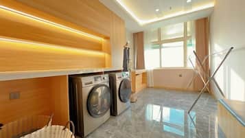 A modern laundry room with a washing machine, dryer, and drying rack.