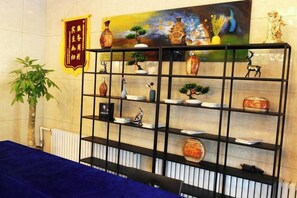 A room with a black metal shelf displaying various decorative items, a blue tablecloth, and a plant. - Mit Holiday Inn (Taiyuan Jianshe South Road Railway Station) (Taiyuan)