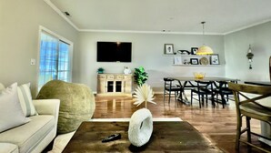 A living room with a sofa, coffee table, and a dining area with chairs and a table. - Spacious 8br/5.5ba home in Rehoboth Beach. WiFi, Pool, Pet friendly, Renovated. (Rehoboth Beach)