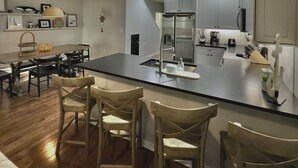 A modern kitchen with a central island, wooden chairs, and built-in cabinets. - Spacious 8br/5.5ba home in Rehoboth Beach. WiFi, Pool, Pet friendly, Renovated. (Rehoboth Beach)