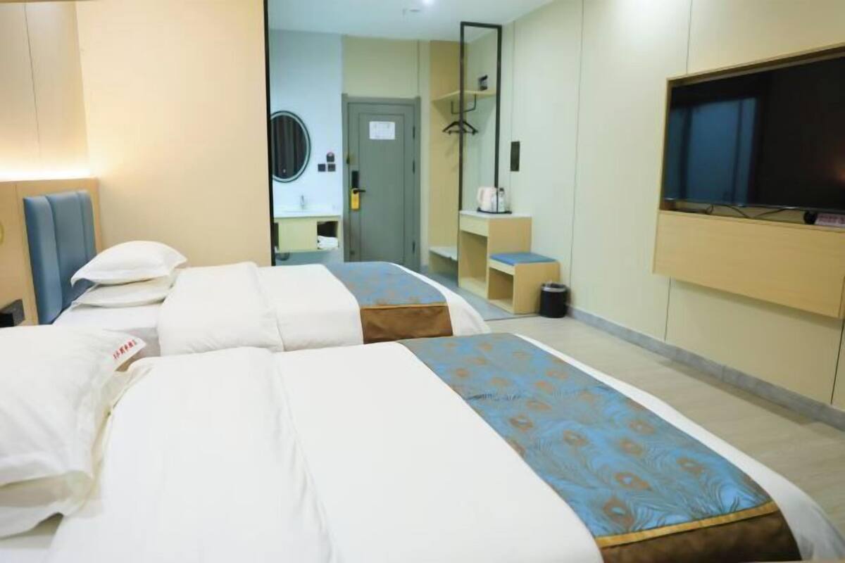 A hotel room with two beds, a TV, a mirror, and a small desk.