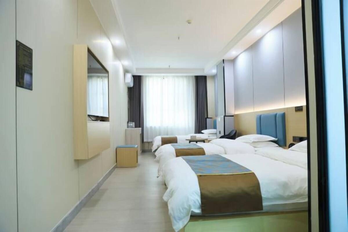 A hotel room with a large bed, a desk, a chair, and a mirror.