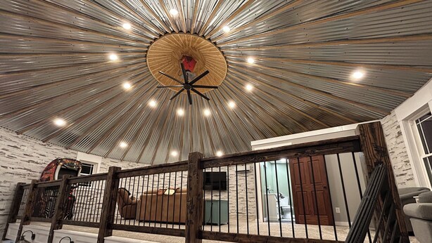 A spacious room with a high ceiling featuring a radial design and multiple light fixtures. There is a wooden staircase with a railing leading to an upper level. - The Ca BIN (Charleston)