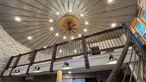A high ceiling with radial lighting, a wooden balcony railing, and a view of the interior space. - The Ca BIN (Charleston)