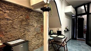 Een moderne keuken met een stenen muur, een centrale kolom, een eettafel en een koelkast.