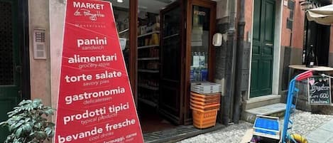 Eingang zu einem Markt, Schild mit Lebensmitteln wie Panini, Salami und Käse.