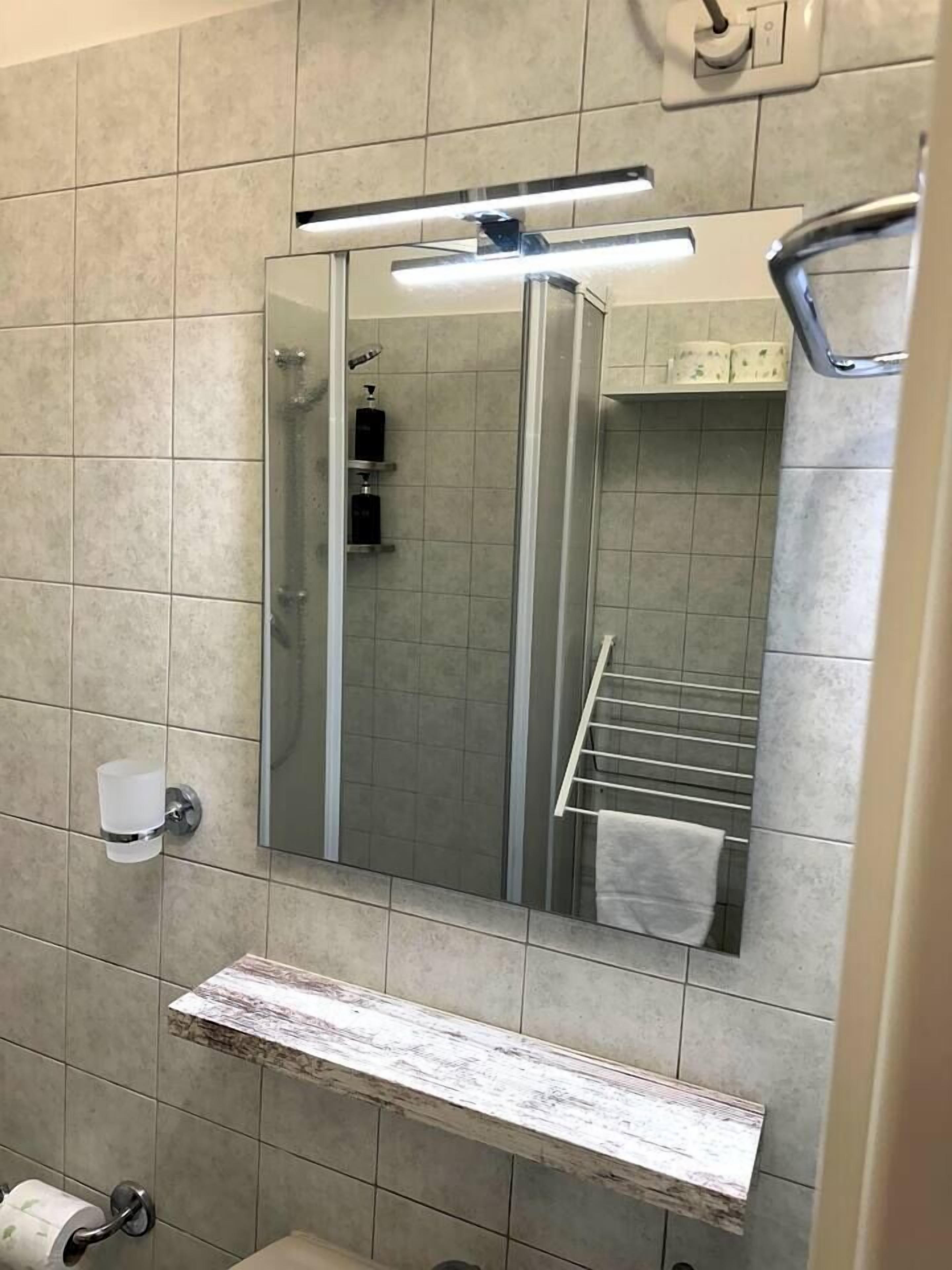 Ein modernes Badezimmer mit Duschkabine aus Glas, Handtuchhalter, Seifenspender und Toilettenpapierhalter.