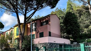 Ein mehrstöckiges Gebäude mit einer rosa und gelben Fassade, einem verschlossenen Eingang und einer Steinmauer im Hintergrund.