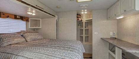 A compact bedroom with a bed, a small kitchenette, and a walk-in closet.