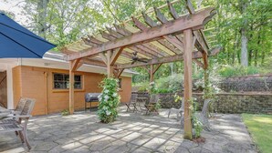Een terras met stenen vloer, een houten pergola en tuinmeubilair.