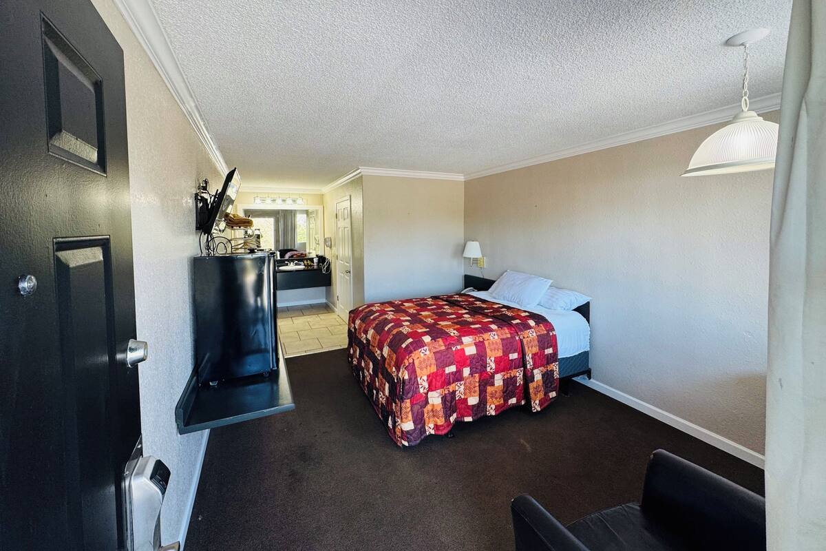 A compact hotel room with a bed, a desk, and a chair.