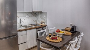 A modern kitchen with a built-in refrigerator, stainless steel sink, and a wooden dining table with white chairs. - Coastline of Paradise Luxury (hrakleion)