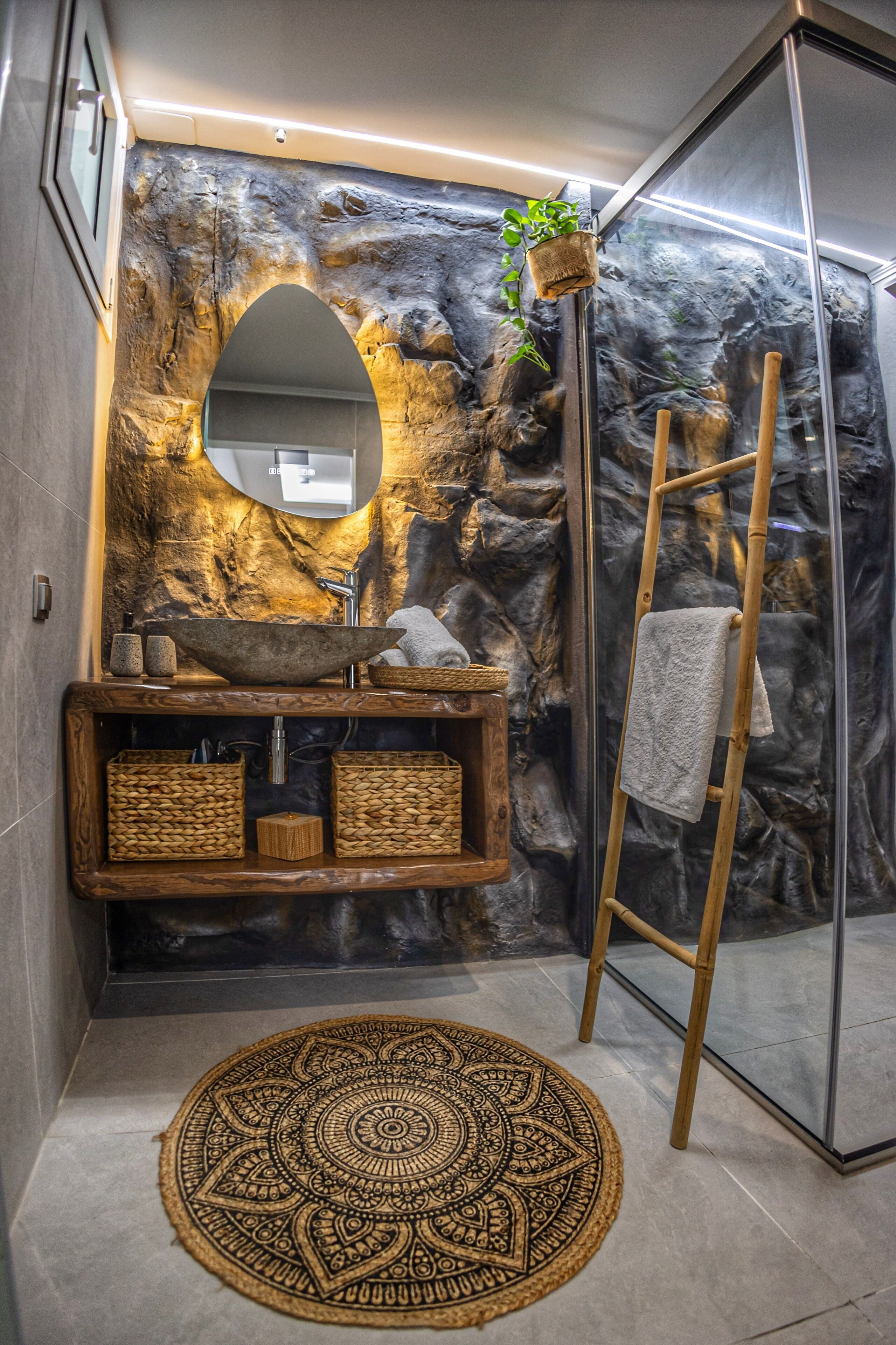 Un baño con pared de piedra, tocador de madera y un espejo grande.