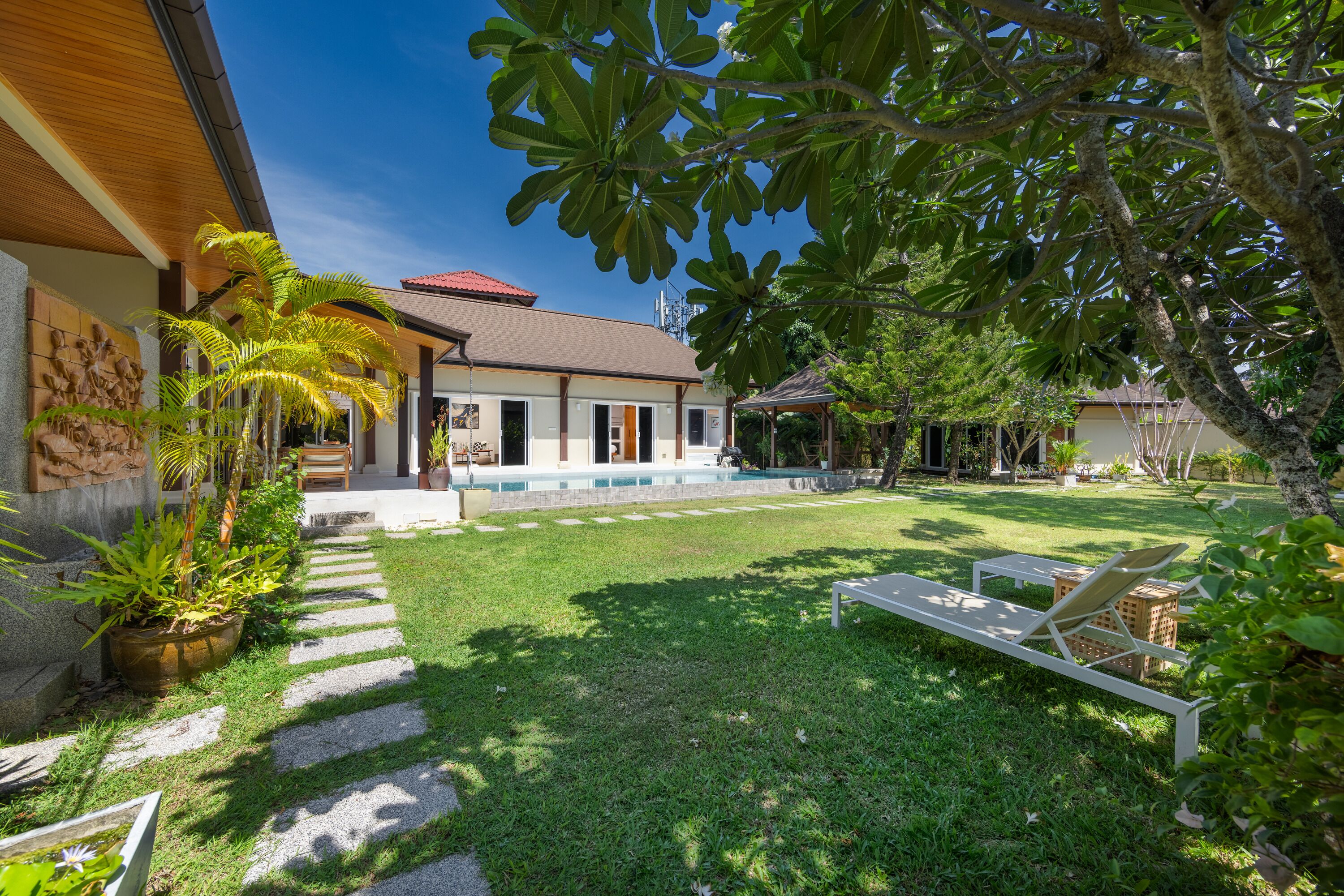 Une maison dotée d’un patio couvert, d’une piscine et d’une pelouse bien entretenue.