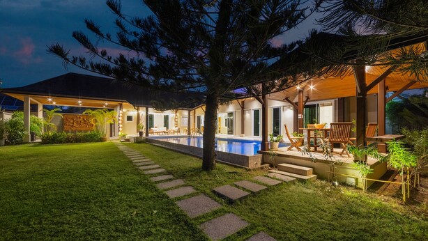 A modern house with a swimming pool, outdoor seating, and a well-lit garden at dusk. - Villa Emilia with Private Pool (Rawai)