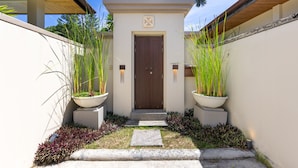 A modern entrance with a wooden door, potted plants, and a concrete pathway leading to the door. - Villa Emilia with Private Pool (Rawai)