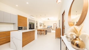 A modern kitchen with a marble island, wooden cabinets, and a large round mirror. - Villa Emilia with Private Pool (Rawai)
