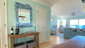 A living room with a wooden console table, a mirror, and a view of the ocean through large windows.