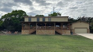 A two-story house with a covered porch and a garage. - A cozy & charming, German-style home in the heart of the Texas Hill Country (Kerrville)