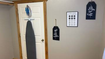 A door with a hanging iron and a towel rack, a framed sign with laundry icons, and a tag with a signature.