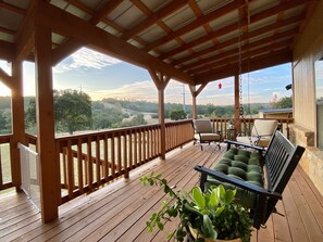 Eine überdachte Holzterrasse mit Holzgeländern, einer Bank und Stühlen.