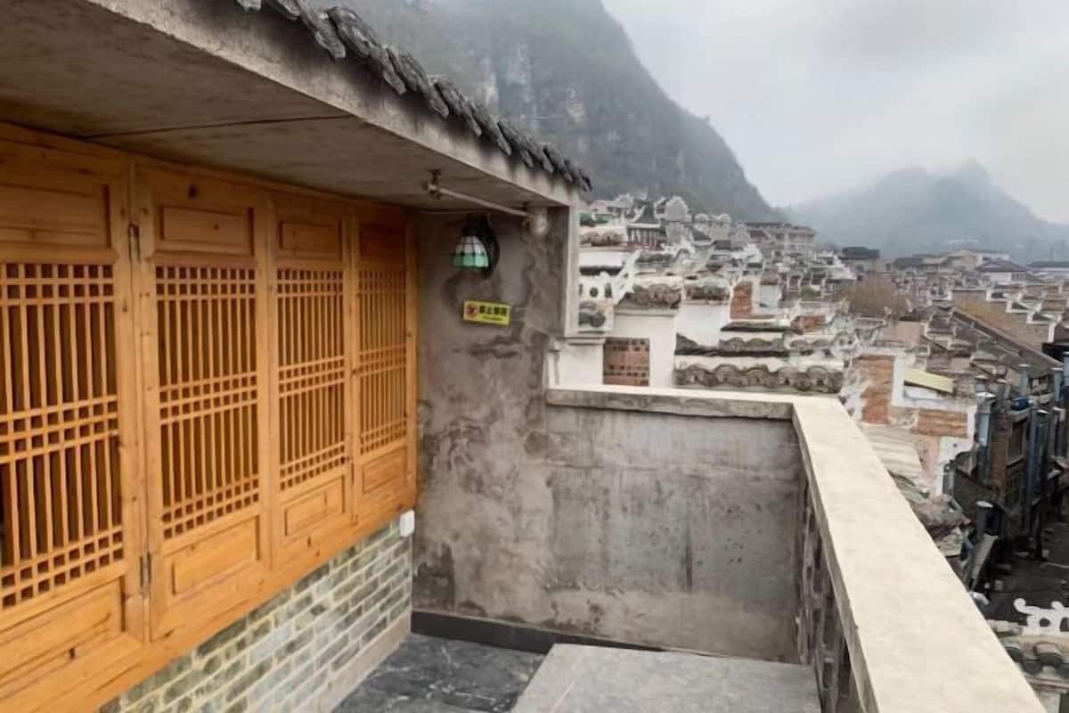 A traditional building with wooden doors and a stone wall, overlooking a densely packed village with tiered houses.