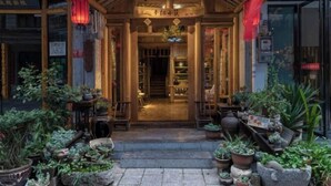 A traditional wooden building with a covered entrance, potted plants, and a sign with Chinese characters. - Mengqi Xiaozhu Inn (Zhenyuan County)