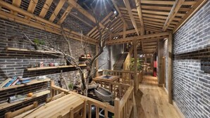 A rustic interior with exposed wooden beams, brick walls, and a wooden deck area. - Mengqi Xiaozhu Inn (Zhenyuan County)