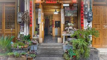 Una entrada tradicional japonesa con puerta de madera, escalones que conducen a la recepción y diversas plantas y decoraciones.