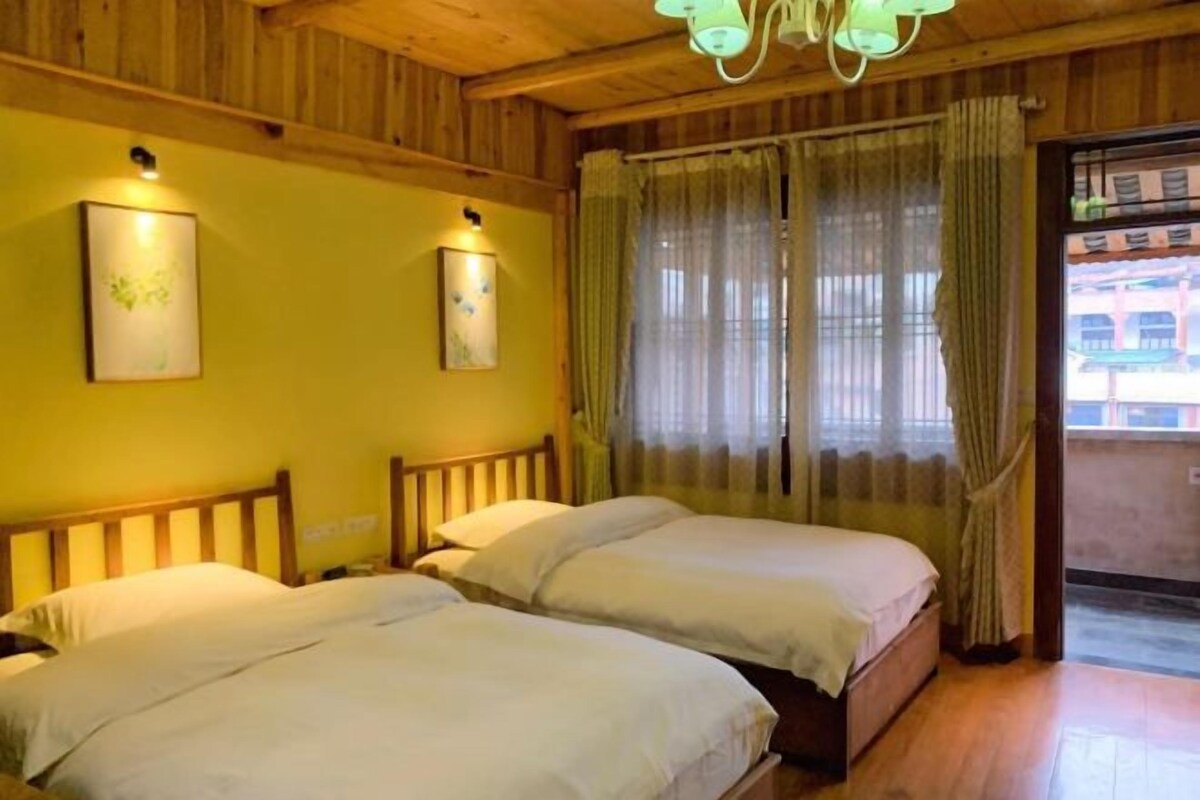 Una habitación con dos camas, cabeceros de madera, una araña y una ventana con cortinas.