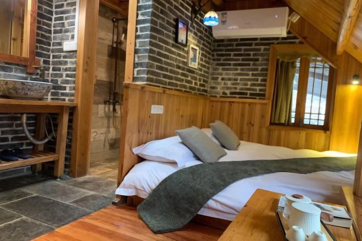 Una habitación acogedora con una cama, paredes de madera, una ventana y un estante con zapatos.