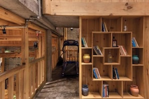 A narrow hallway with wooden shelving units containing books and pottery. - Mengqi Xiaozhu Inn (Zhenyuan County)