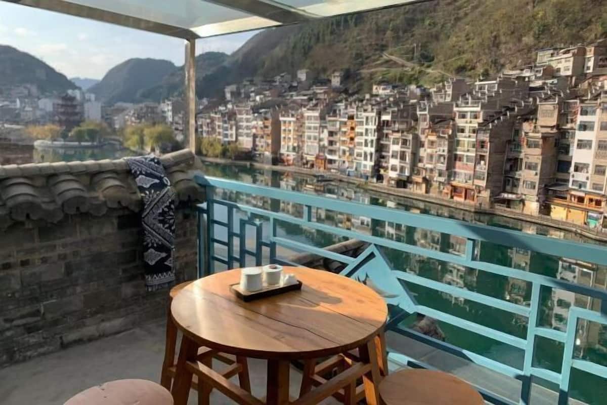 A balcony with a wooden table and chairs, overlooking a densely packed town with traditional buildings.