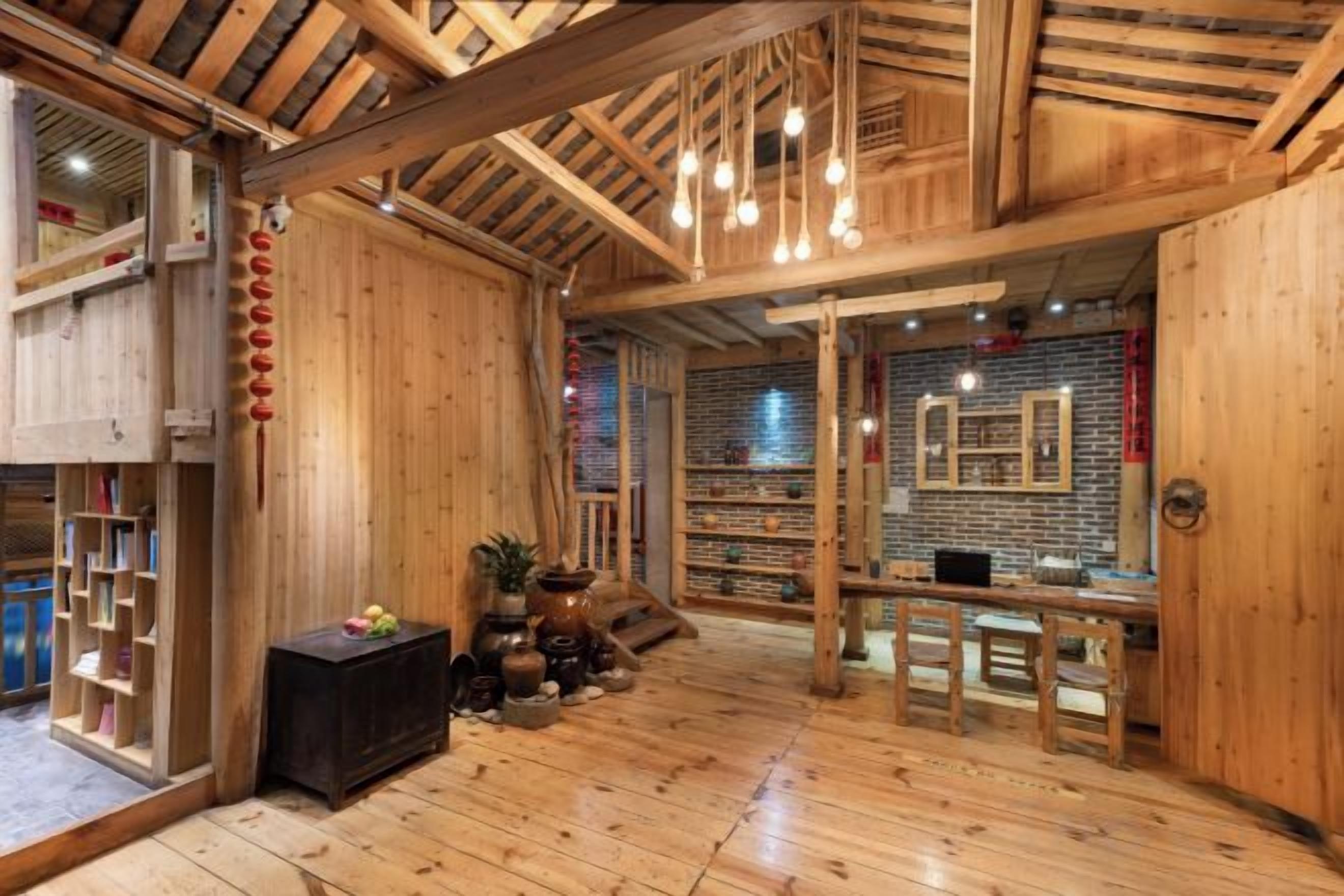 Un intérieur en bois avec un plafond haut, un espace salon central et un mur de briques orné de tableaux encadrés.