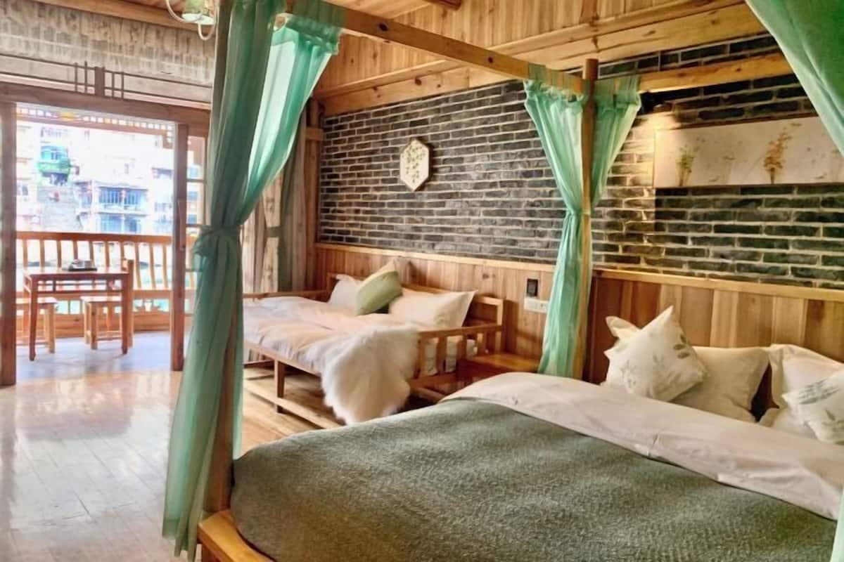 A wooden room with a bed, a bench, and a brick wall.