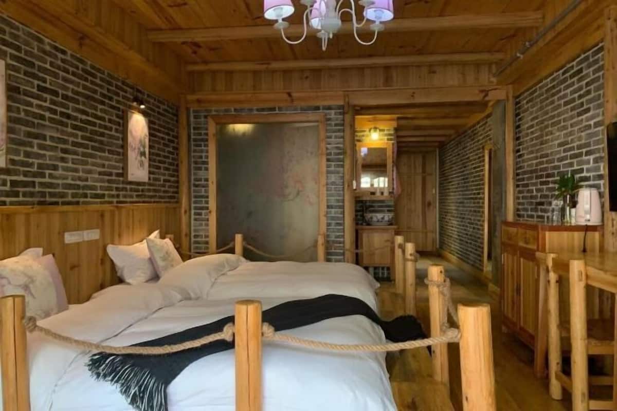 A wooden cabin-style room with a bed, wooden walls, and a chandelier.