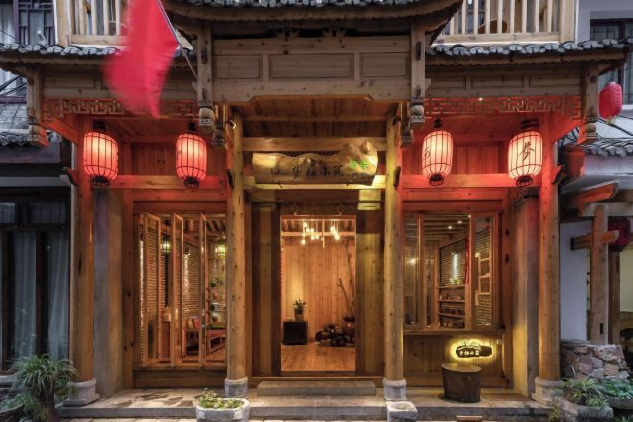 A traditional wooden building with a wooden entrance, lanterns, and a signboard.
